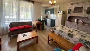 Ein kompakter Wohnbereich mit Sofa, Esstisch, Küchenzeile und eingebauten Schränken.