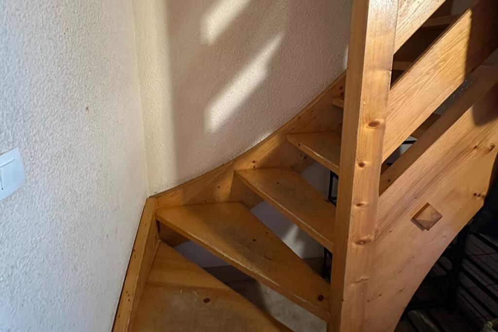 Eine Holztreppe mit Handlauf, die zu einer niedrigeren Ebene führt.