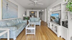 Una sala de estar con sofá, mesa de centro y mueble para televisión.