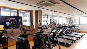 A gym with multiple treadmills and elliptical machines, large windows, and a sign on the wall. - Charming 1-bedroom apartment with AC, WiFi in peaceful Bela Vista Porto Alegre (Rio Branco Porto Alegre)