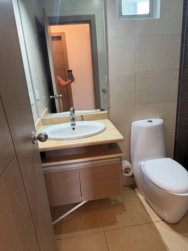 A bathroom with a white sink, a toilet, and a mirror.