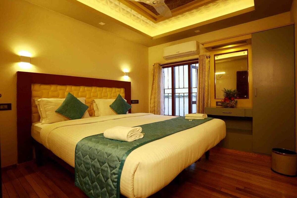 A hotel room with a large bed, a vanity with a mirror, and a window with curtains.