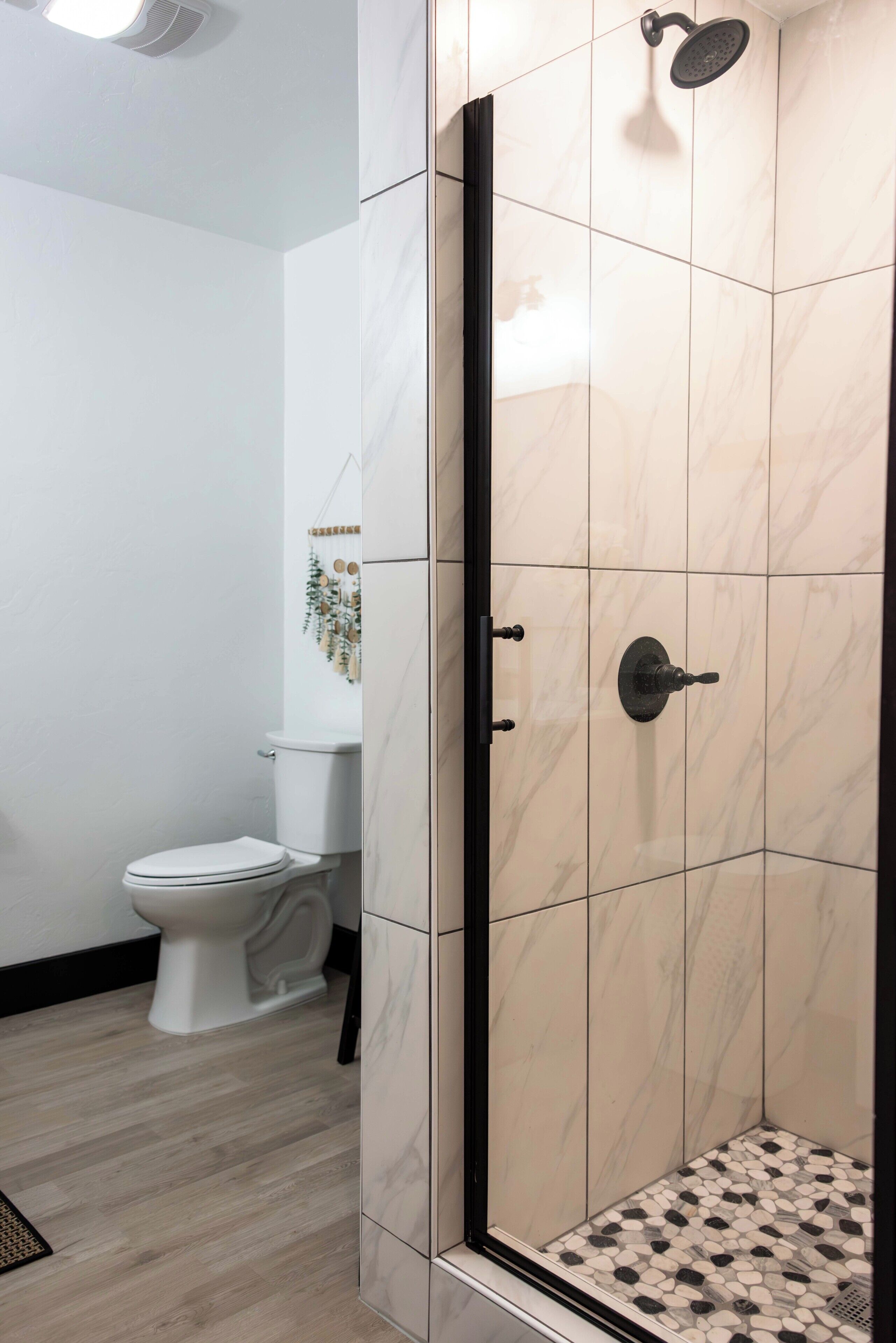 Une salle de bain moderne avec une douche à parois de verre, des toilettes blanches et un élément décoratif mural.