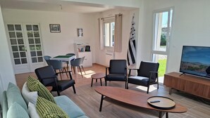 Una sala de estar moderna con un sofá, sillas, una mesa de centro y un televisor.