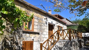 A stone building with a wooden staircase and a metal railing. - Assos Assinos (Behram)