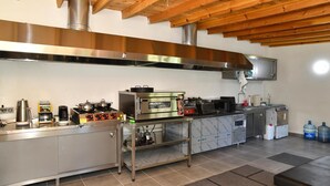 A commercial kitchen with stainless steel appliances, a wooden ceiling, and tiled flooring. - Assos Assinos (Behram)