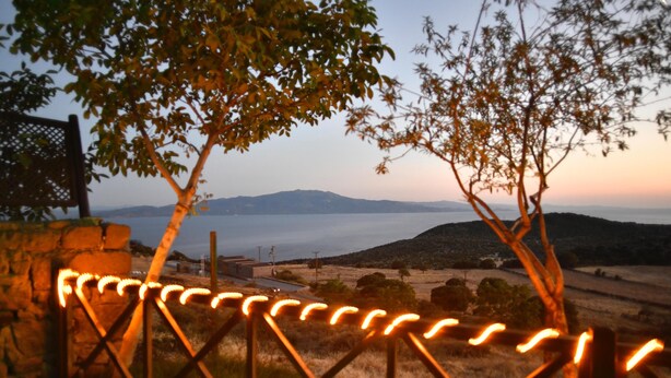 A view of a coastal landscape with a stone wall and a metal gate in the foreground. - Assos Assinos (Behram)