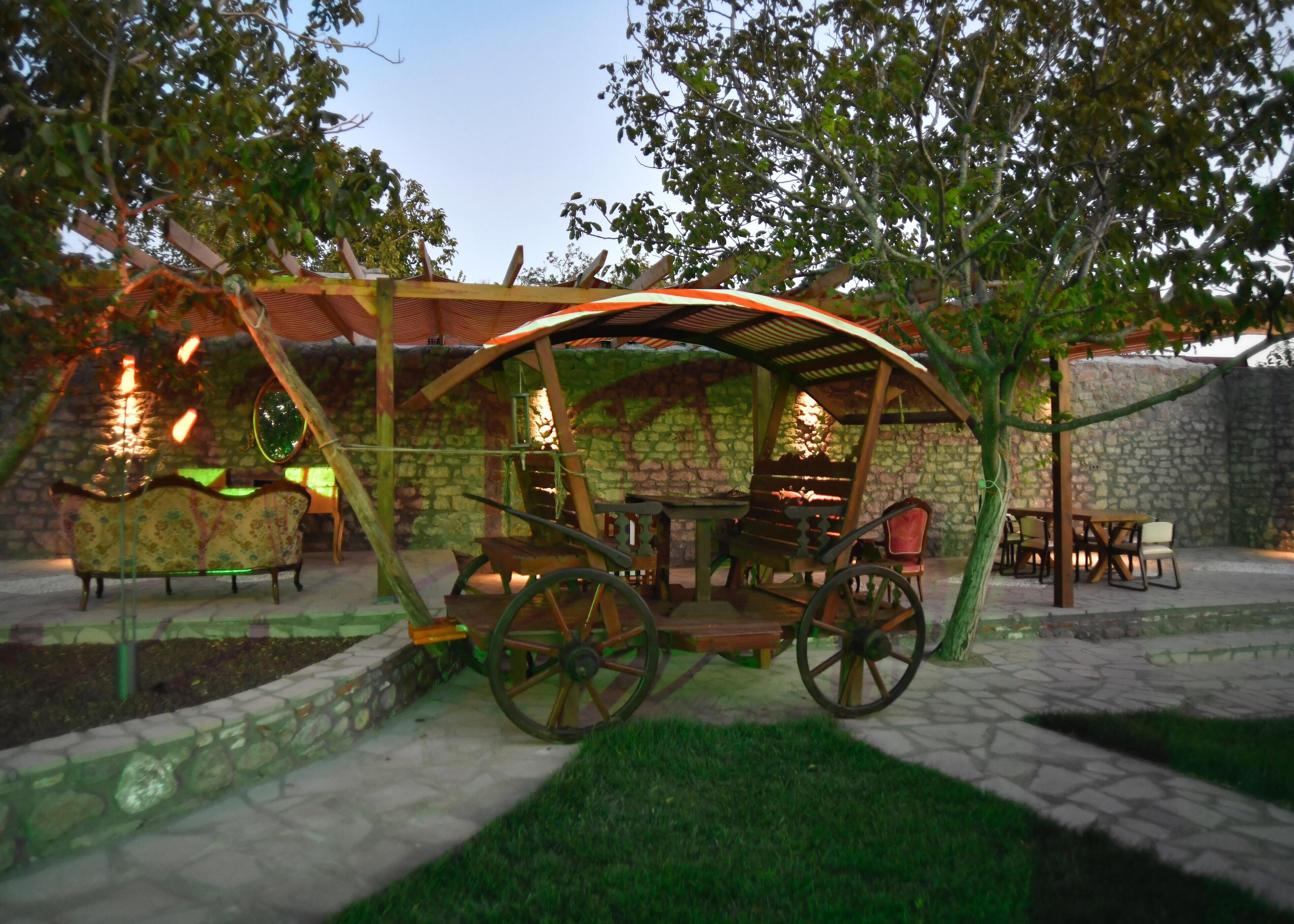 Un área de estar al aire libre con un muro de piedra, muebles de madera y un carrito.