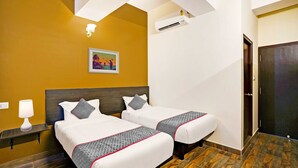 Ein Hotelzimmer mit zwei Betten, einem Nachttisch, einer Wandklimaanlage und einem Bild an der Wand.