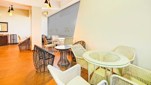 Ein stilvoller Lounge-Bereich mit Korbmöbeln, Glastischen und Pendelleuchten.