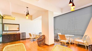 Ein modernes Interieur mit Rattanmöbeln, einem Essbereich und einem großen Fenster mit Blick auf Stromleitungen.