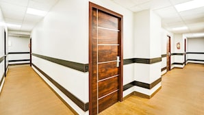 Ein Flur mit Holztüren, weißen Wänden und einer gefliesten Decke.