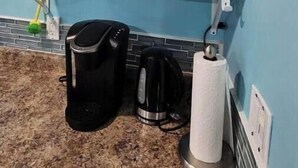 A kitchen with white cabinets, a coffee maker, a kettle, and a paper towel holder.
