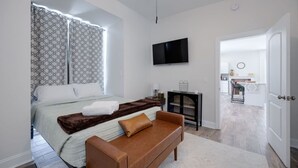 Ein modernes Hotelzimmer mit Bett, Fernseher, kleinem Tisch und einer Couch.