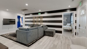 A modern living room with a sectional sofa, a flat-screen TV, and a patterned rug. - Comfortable group stay walkable to Vanderbilt Stadium (Nashville)