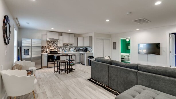 A modern apartment with a kitchen, living room, and a TV mounted on the wall. - Comfortable group stay walkable to Vanderbilt Stadium (Nashville)