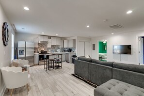 A modern apartment with a kitchen, living room, and a TV mounted on the wall. - Comfortable group stay walkable to Vanderbilt Stadium (Nashville)