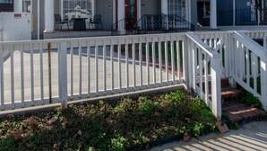 A two-story residential building with a covered front porch and a white fence. - Comfortable group stay walkable to Vanderbilt Stadium (Nashville)