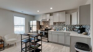 A modern kitchen with white cabinets, a black and white backsplash, and stainless steel appliances. - Comfortable group stay walkable to Vanderbilt Stadium (Nashville)