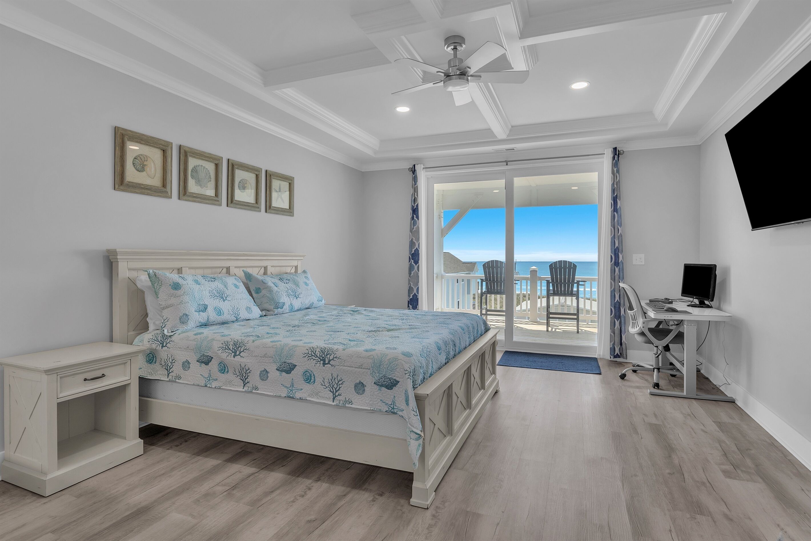 Quarto com cama, escrivaninha, cadeira e televisão. Tem um varanda vista para o mar.