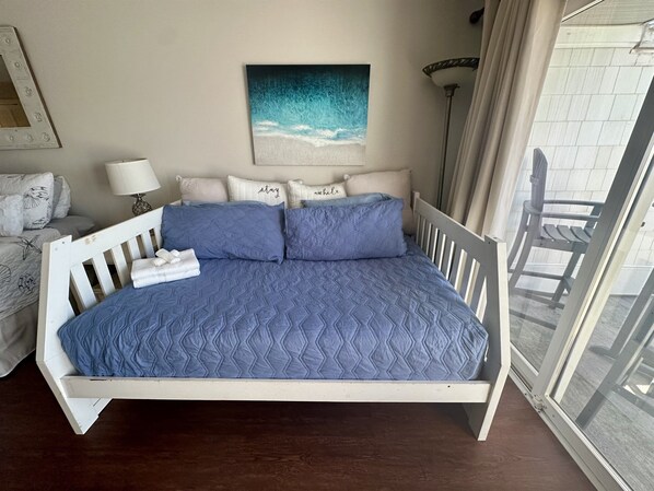 A bed with a blue quilt, white headboard, and pillows with text. - Queens Grant Sea Queen in Queens Grant 2 bed/2 bath (Topsail Beach)