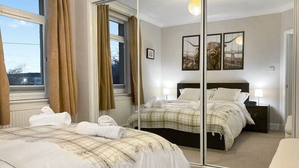 Ein Hotelzimmer mit einem großen Bett, einem Spiegel, zwei Nachttischen und Blick ins Freie.