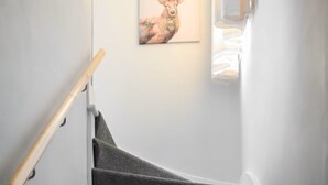 Eine Treppe mit hölzernem Geländer und Teppichstufen, die zu einer Empore führen.