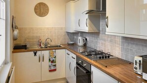 Eine moderne Küche mit weißen Schränken, einem Gasherd, einem Wasserkocher und einem Toaster.