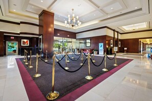 A hotel lobby with a red carpet, golden stanchions, and a chandelier. - 7th-Floor 1BR Suite, MGM Signature — Strip Balcony, No Resort Fee (LAS VEGAS)