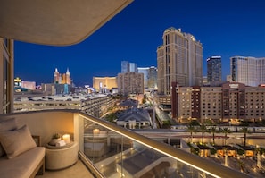 Um hotel alto com varanda e vista para a paisagem urbana à noite.