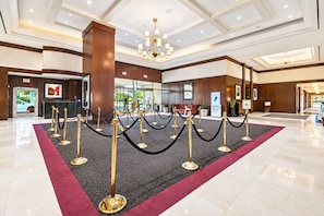 Eine Hotelhalle mit einer Rezeption, einem Chandelier und einem Teppichbereich in Rot.