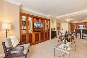 A hotel room with a TV, seating area, and kitchenette.