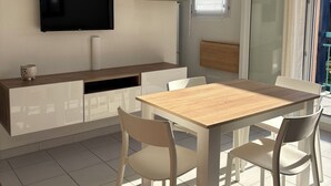 Una cocina moderna con televisión integrada, armarios blancos y una mesa de comedor de madera con sillas.