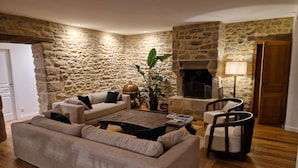 Una sala de estar acogedora con una pared de piedra, una chimenea, un sofá, una mesa de centro y una silla.