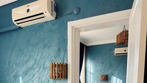A bedroom with a bed, bedside table, and a wall-mounted air conditioner.