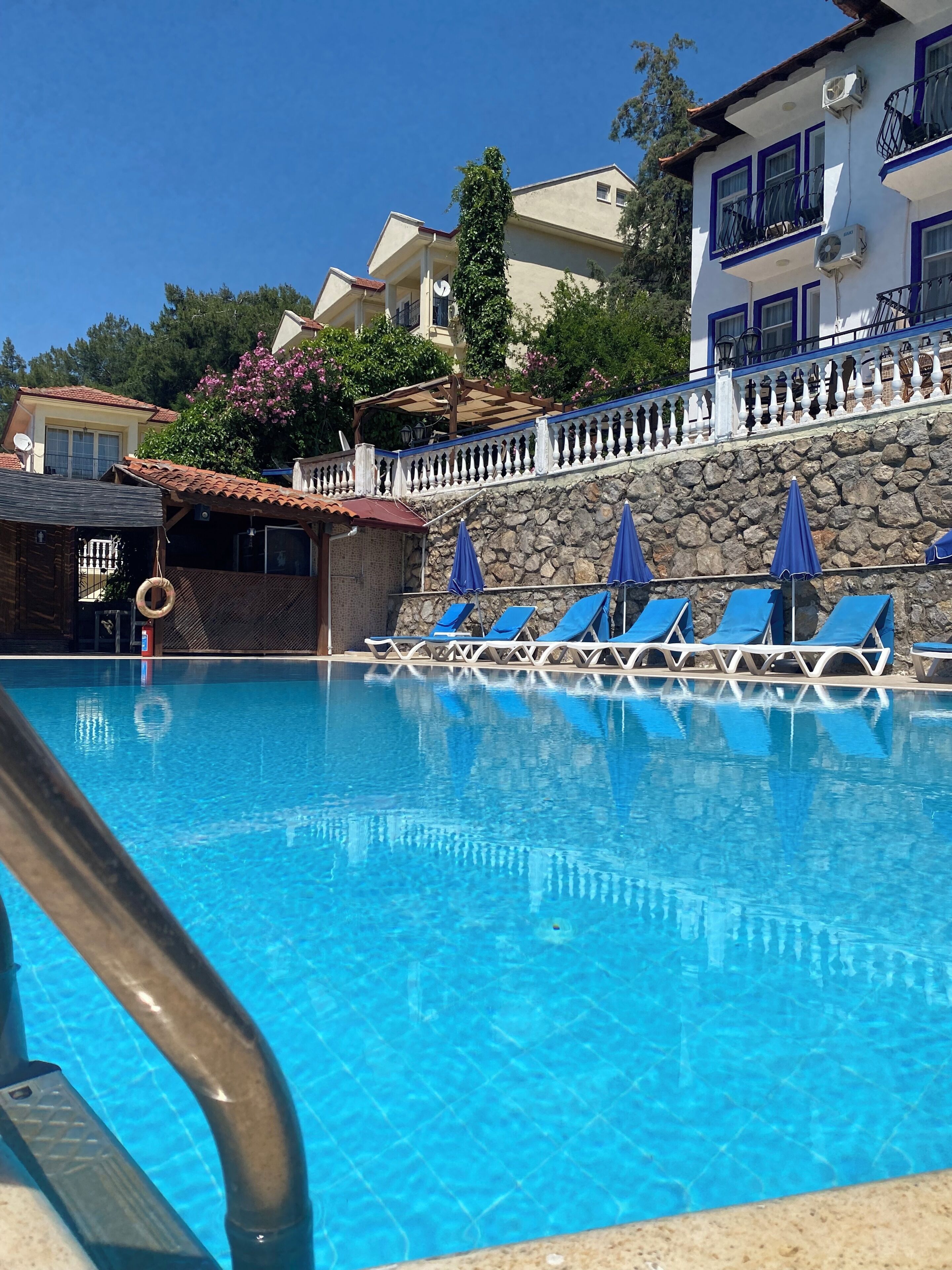 Ein Pool mit blauen Liegestühlen und einer Steinwand.
