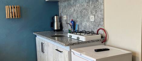 A compact kitchen with a refrigerator, stove, and cabinets.