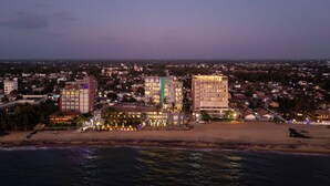 Un paisaje urbano costero al atardecer, con edificios, una playa y vista al océano.