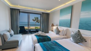Habitación de hotel con dos camas, un sofá, vista a la playa y un cuadro del mar.
