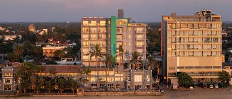 A coastal hotel with multiple floors, balconies, and a beach view.