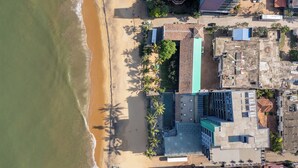 Vista aérea de una zona costera con playa, edificios y palmeras.