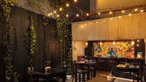 Un restaurante con mesas, sillas, una zona de bar y plantas decorativas.