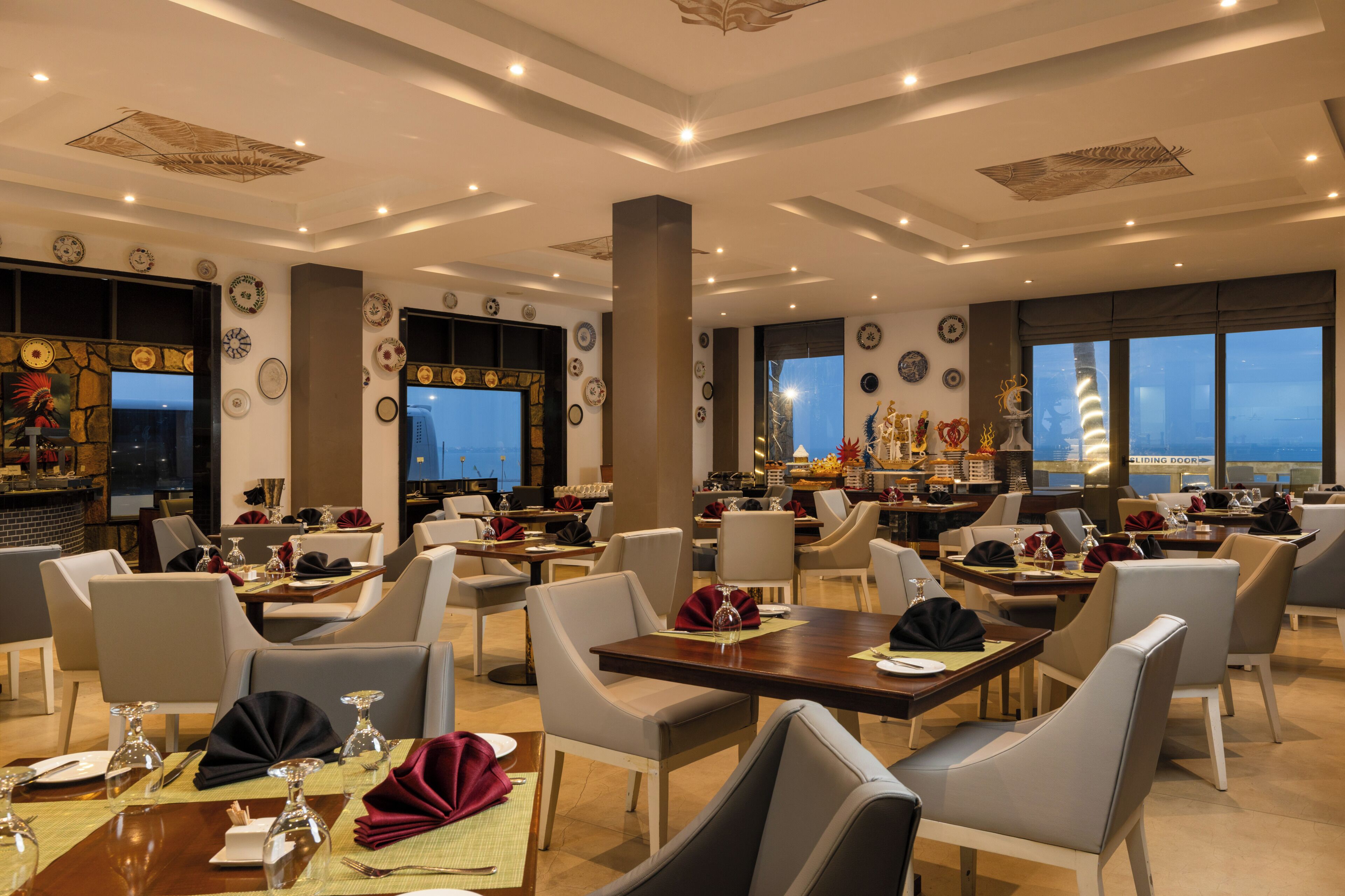 A restaurant with multiple dining tables, chairs, and a view of the cityscape through large windows.