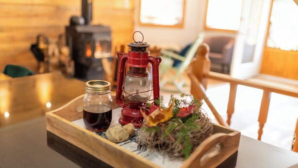 A wooden tray with a red lantern, a glass jar, and a small plant on a table.
