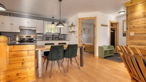 A modern kitchen with white cabinets, a wooden dining table, and black chairs.