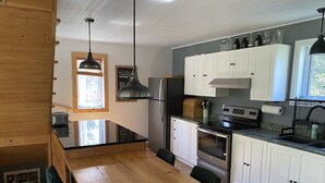 A modern kitchen with white cabinets, stainless steel appliances, and a wooden dining table.