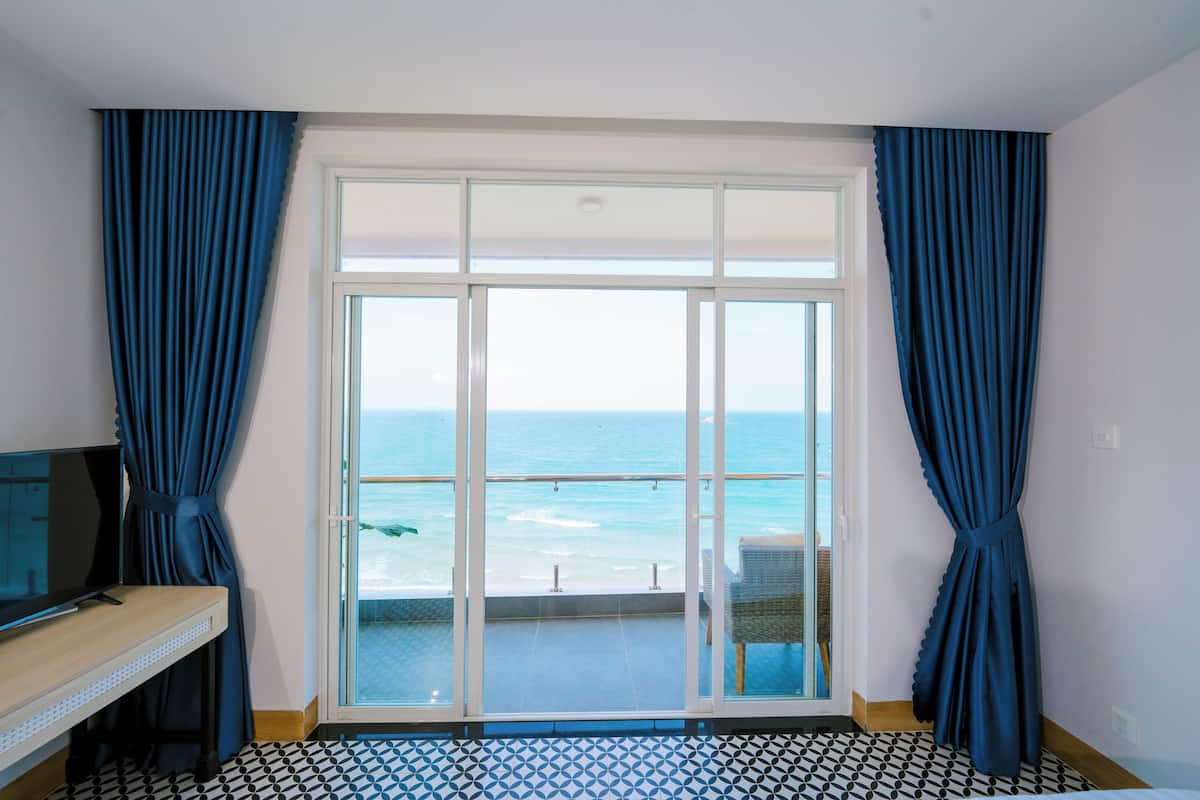 Una habitación con un amplio ventanal corredero que da a un balcón con vistas al océano.
