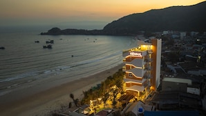 Un hotel sul lungomare con un cartello ben visibile, situato in prima linea sulla spiaggia e adiacente ad altri edifici.