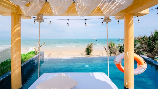 Un'area piscina privata con un lettino, un galleggiante e vista sulla spiaggia.