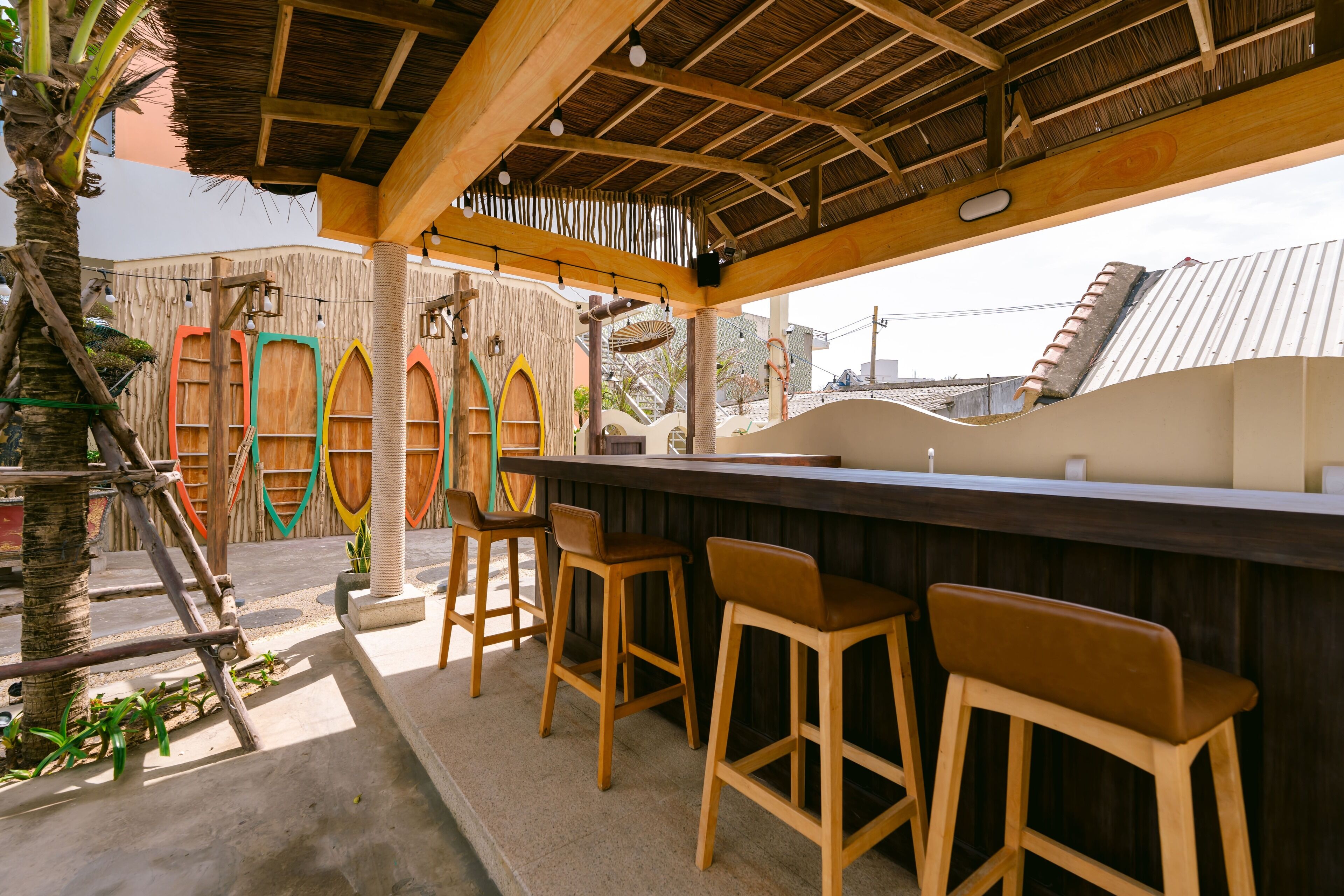Un área de bar al aire libre con taburetes de madera y techo de paja.